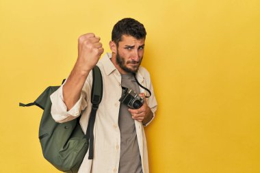 Genç İspanyol seyahat fotoğrafçısı kameraya yumruğunu, agresif yüz ifadesini gösteriyor..