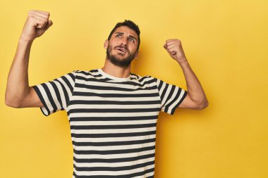Sarı arka planda genç bir İspanyol zaferden sonra yumruk kaldırıyor, kazanan konsept..