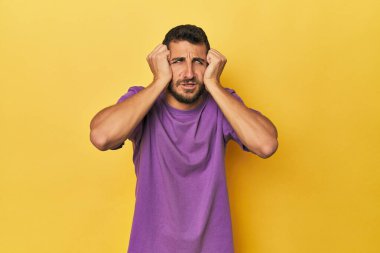 Sarı arka planda ağlayan genç İspanyol bir adam. Acı ve kafa karışıklığı gibi bir şeyden mutsuz..