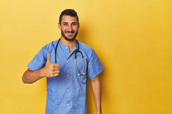 年轻的西班牙男护士年轻的西班牙男护士自信地微笑着 竖起大拇指 图库图片