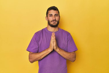 Sarı arka planda genç bir İspanyol dua ediyor, bağlılık gösteriyor, dindar biri ilahi ilhamı arıyor..
