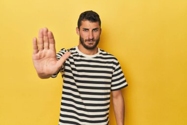 Sarı arka planda genç bir İspanyol, elini uzatmış, dur işareti göstererek seni engelliyor..