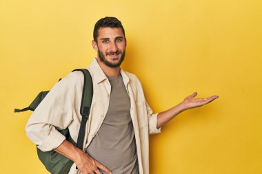 Sırt çantalı genç İspanyol bir adam avucunun içinde bir fotokopi alanı gösteriyor ve belinde başka bir el tutuyor..