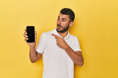 Genç İspanyol adam yan tarafı gösteren bir telefon ekranı gösteriyor.