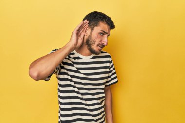 Sarı arka planda genç bir İspanyol bir dedikoduyu dinlemeye çalışıyor..