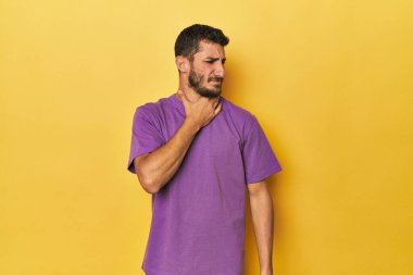 Sarı arka plandaki genç İspanyol adam virüs ya da enfeksiyon yüzünden boğaz ağrısı çekiyor..