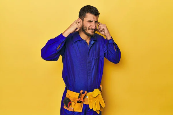 青いジャンプスーツの若いヒスパニック男性 青いジャンプスーツで耳を手でカバー — ストック写真