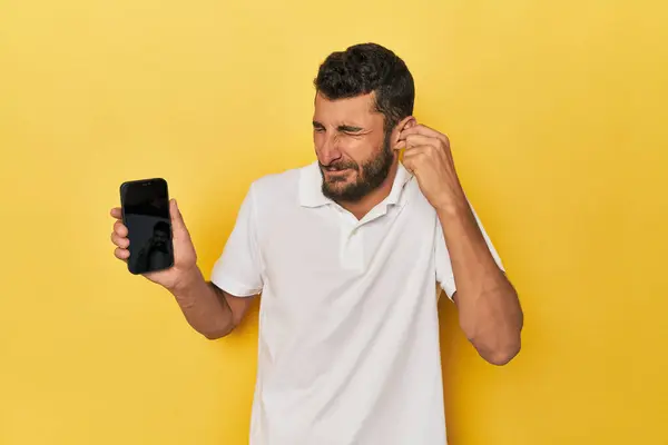 Young Hispanic Man Shows Phone Screen Covering Ears Hands — Stock Photo, Image