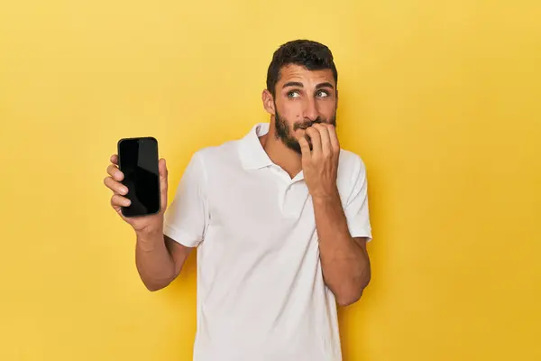 Young Hispanic Man Shows Phone Screen Relaxed Thinking Something Looking — Stock Photo, Image