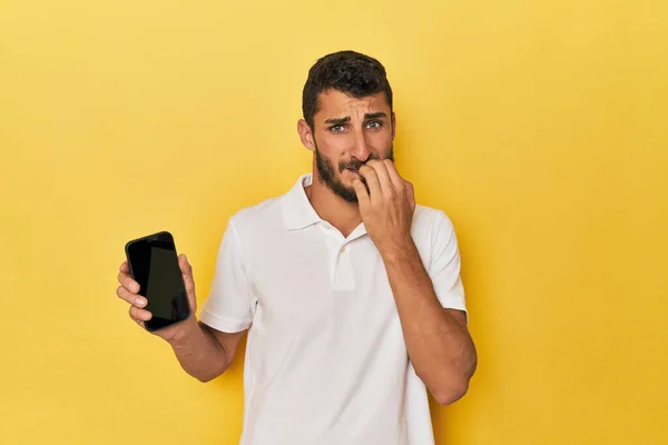 Mladý Hispánec Ukazuje Obrazovku Telefonu Kousání Nehty Nervózní Velmi Nervózní — Stock fotografie