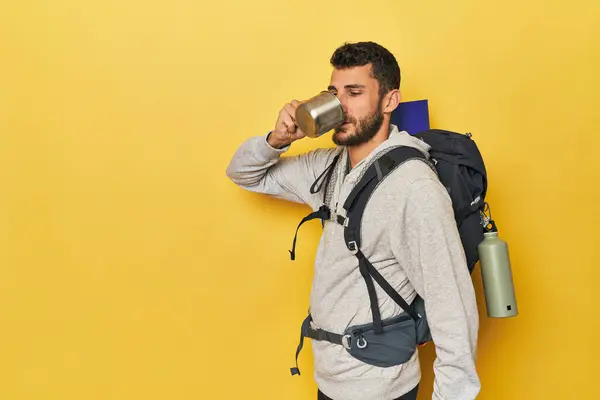 Young Hispanic man with camping mug and pack
