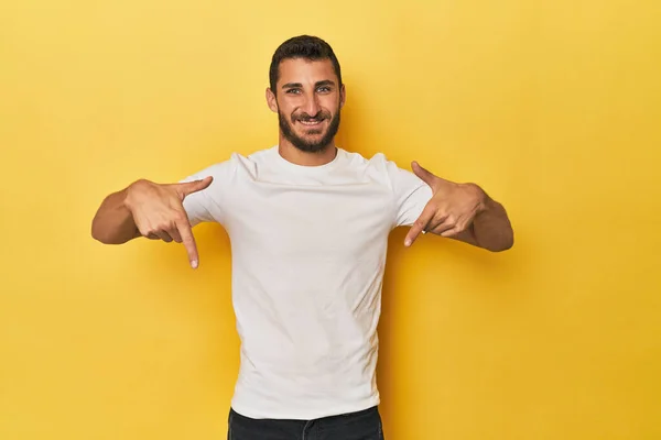 年轻的西班牙裔男子 背景是黄色的 手指头垂下 积极向上 免版税图库图片