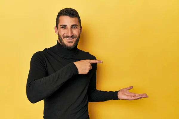 Jonge Spaanse Man Gele Achtergrond Opgewonden Met Een Kopieerruimte Palm Rechtenvrije Stockafbeeldingen