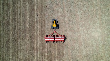 Aerial view of a farmer's tractor doing sowing in the field. Spring, sowing season. Planting crops. clipart