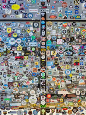 Yolcuların geçişlerini kaydeden çeşitli şekillerde ve boyutlarda çıkartmalarla kaplı bir duvar. Patagonya Arjantin.