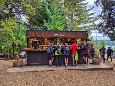 Bariloche, Arjantin, 15 de Abril de 2024: Patagonya bira fabrikasının verandasındaki bir barın etrafında duran bir grup insan.