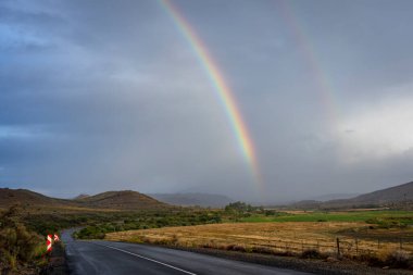 Klaarstroom 'un hemen dışındaki N12 boyunca bir Karoo fırtınasından sonra bir gökkuşağı. Batı Burnu. Güney Afrika