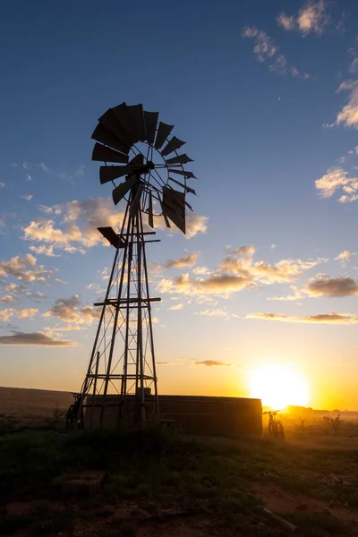 stock image eBike (mountain bike) leaning against a reservoir at a windmill during sunset. Vanrhynsdorp Western Cape. South Africa.