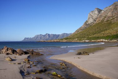 Muhteşem Rooi Els plajı manzarası ve arka planda Kogelberg Dağları ve Clarence Yolu olan haliçler manzarası. Batı Burnu. Güney Afrika