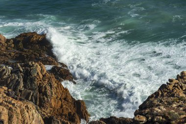 Okyanus dalgalarının, batı Cape Town yakınlarındaki Gordons Körfezi ile Rooi-Els arasındaki Clarence Yolu boyunca uzanan engebeli kayalık kıyı şeridi üzerindeki hava manzarası. Güney Afrika