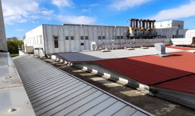 Bükülmüş metal levha içindeki endüstriyel bir binanın eski çatısındaki teknik sistem.