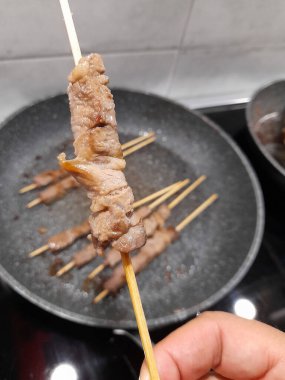 Mutfaktaki bir adamın elinde et şişi.