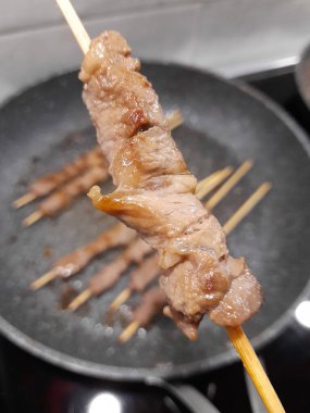 Mutfaktaki bir adamın elinde et şişi.