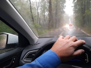 Sonbaharda yağmurlu bir günde arabasını süren adam.