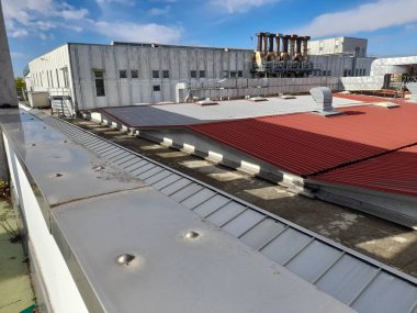 Terk edilmiş bir sanayi deposunun eski yalıtılmış metal çatısı.