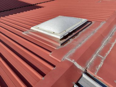 Terk edilmiş bir sanayi barakasının çatı penceresi ve su geçirmez kılıfların durumu nedeniyle bariz sızma sorunları var.