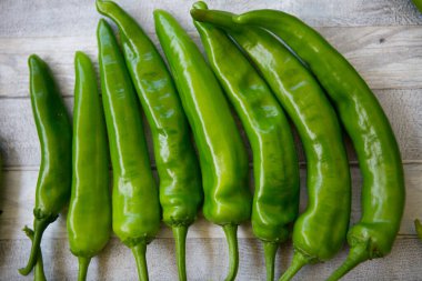 Acı kırmızı biberli arka plan. Gri ahşap arka planda yeşil biberler. Sağlıklı gıda konsepti.