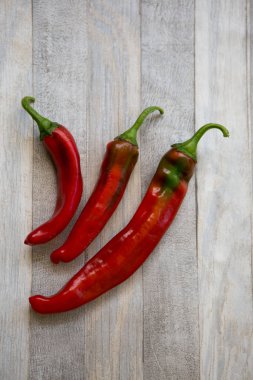 Acı kırmızı biberli arka plan. Gri ahşap masa arkasında kırmızı biberler. Sağlıklı gıda konsepti.