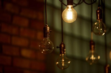 Yanan bir ampul bulanık sarı ışıkların arka planında hafifçe parlar. Enerji krizi. Kesinti.