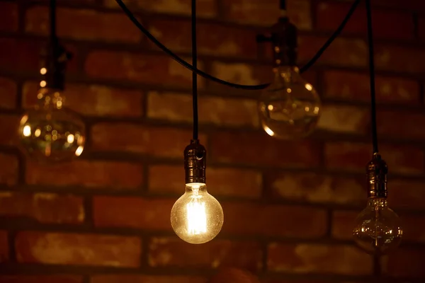 A burning light bulb glows faintly against the background of blurry yellow lights. Energy crisis. Blackout.