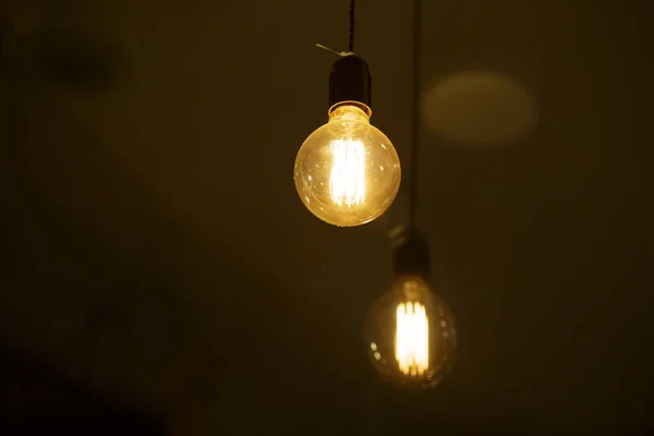 Yanan Bir Ampul Bulanık Sarı Işıkların Arka Planında Hafifçe Parlar — Stok fotoğraf