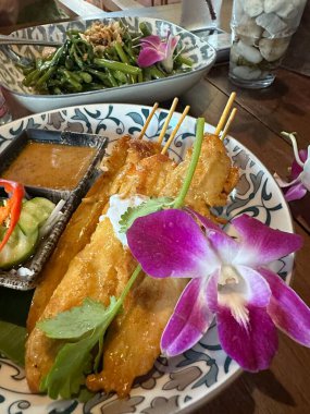 Üzerinde canlı bir çiçeğin bulunduğu güzel bir yemek tabağı, sanatsal olarak bir masada sunuluyor.