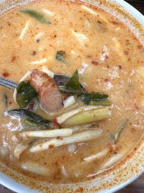 Bu, Tom Yum 'un içine bir çatal yerleştirilmiş lezzetli bir çorba kasesinin yakından görüntüsü, keyif ve lezzet için hazır.
