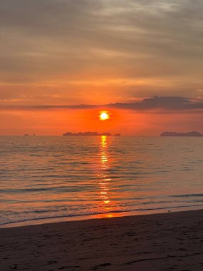 Güneş yavaş yavaş engin okyanusun üzerinde batıyor. Sıcak renkleri aşağıdaki ışıldayan suya güzel bir şekilde yansıyor.