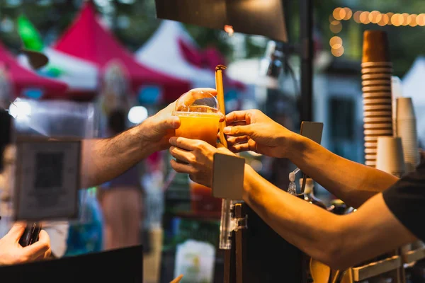 Male bartender serving healtyh drink to customer in plastic takeaway glass