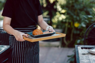 Waitress serving croissants in the coffee shop outdoor