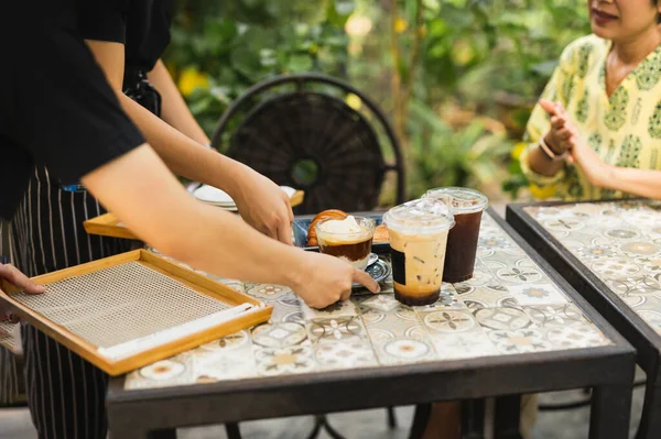 Waiter delivery iced coffee drink to customer in cafe outdoor