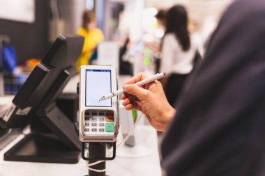 Consumers women signing on a touch screen of credit card transaction machine at supper market