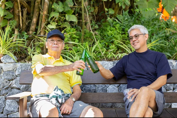 Father and son sitting in chairs and drinking beer on vacation