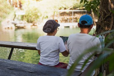 Couple working on laptop computer sitting on the floor outdoor with river in background