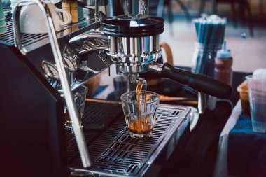 Espresso makinesi kafede bardağa kahve dolduruyor.