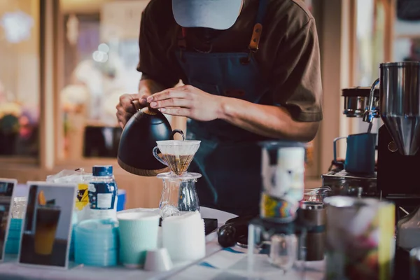 Barista damlayan kahve yapmak için sıcak su dolduruyor.