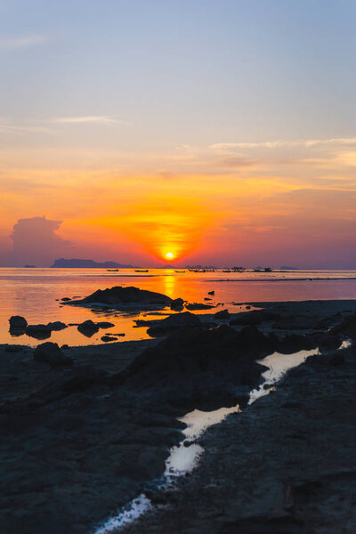 Vertical of silhouette fishing boats at sunset in the sea