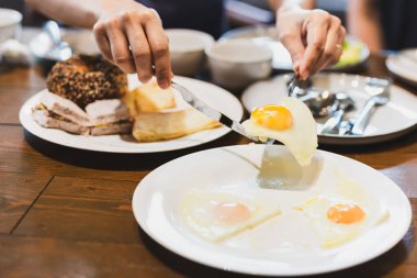 Ahşap masada arkadaşlarıyla omlet yiyen bir kadın.