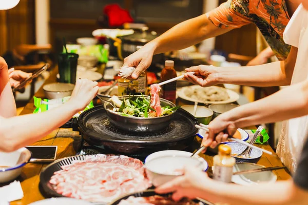 一群朋友在家里煮中国泡菜火锅 免版税图库照片