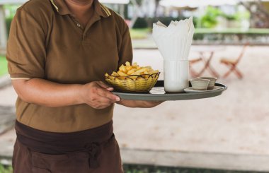 Garson açık hava restoranındaki tepside patates kızartması servis ediyor.